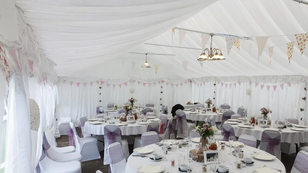 White party tent set with round tables, linens and chairs, a classic setup for backyard party rentals in NJ