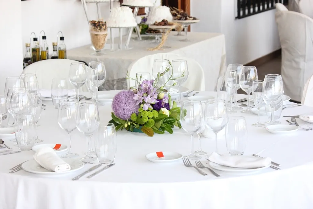 Round table with a white tablecloth, glasses and a small flower centerpiece