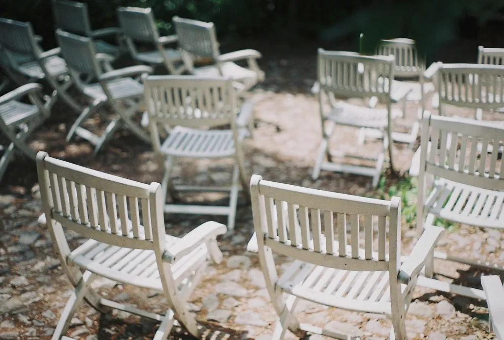White wooden folding chairs set up outdoors on a gravel patio