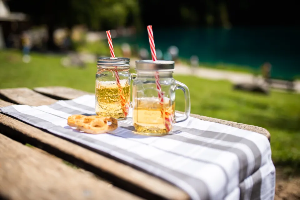 Two glass mugs of iced tea with striped straws on an outdoor table