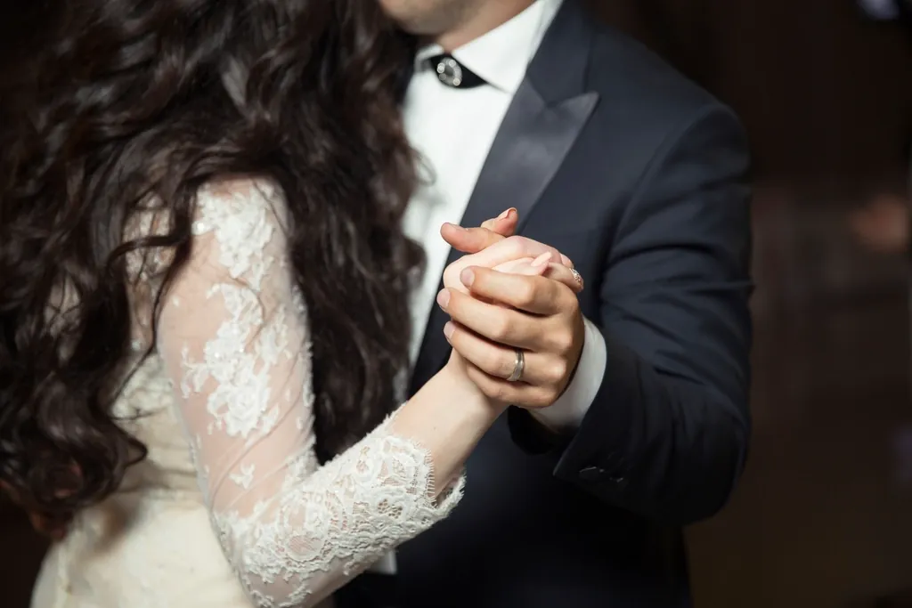 Bride and groom holding hands in a closed dance position