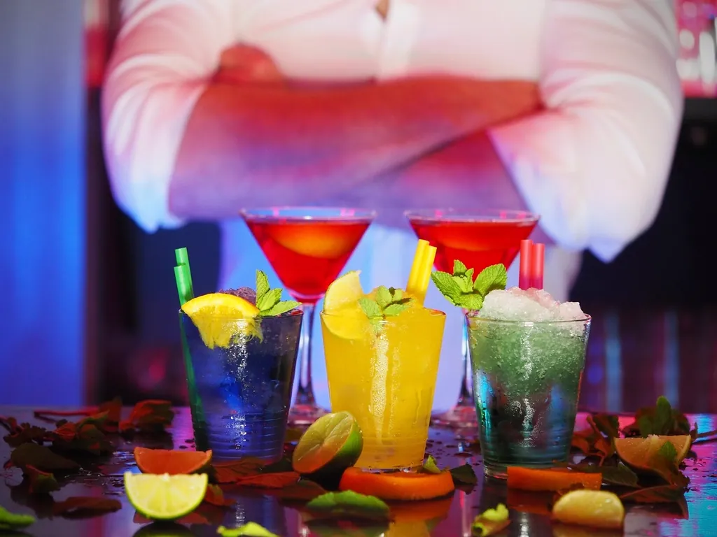 Row of colorful cocktails with fruit garnishes on a bar