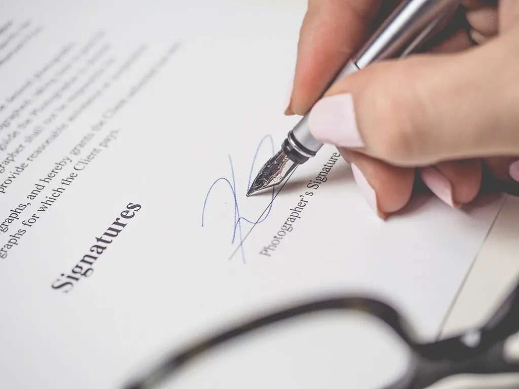 Hand signing a printed document with a silver fountain pen
