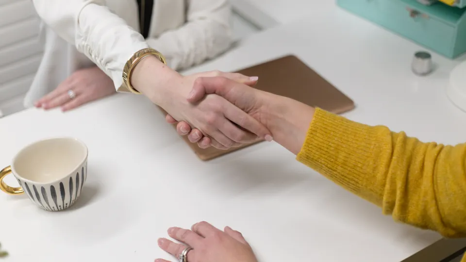 Two people shake hands across an office desk at the start of a commercial loan in NJ