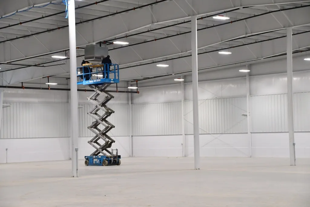 Empty warehouse interior with a worker on a scissor lift