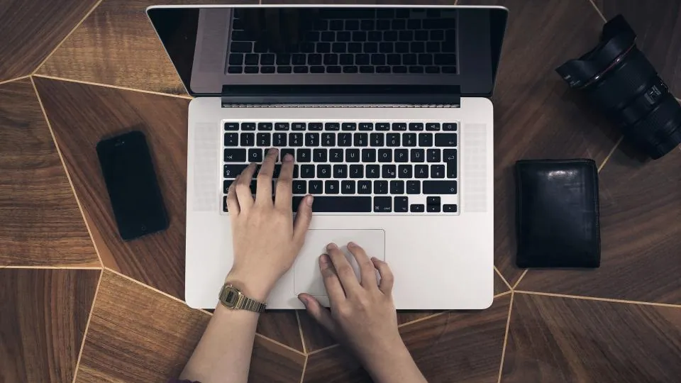 Owner typing on a laptop at a wooden desk while setting up CRM automation for small business