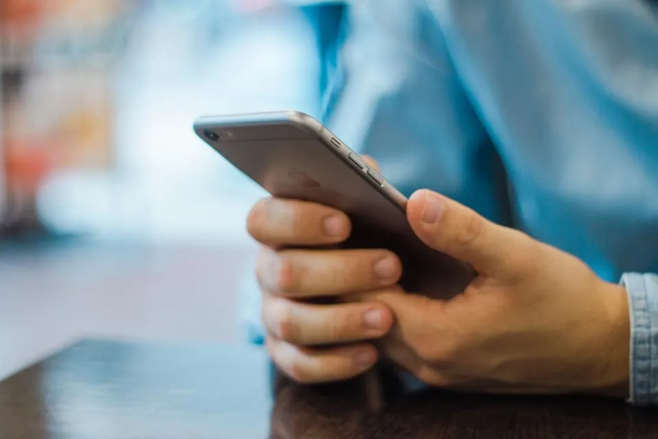 Hands holding a smartphone over a table