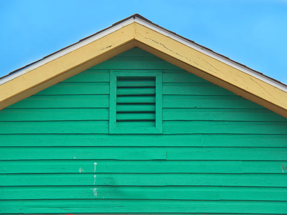 Green wood siding and a yellow-trimmed gable with a louvered vent