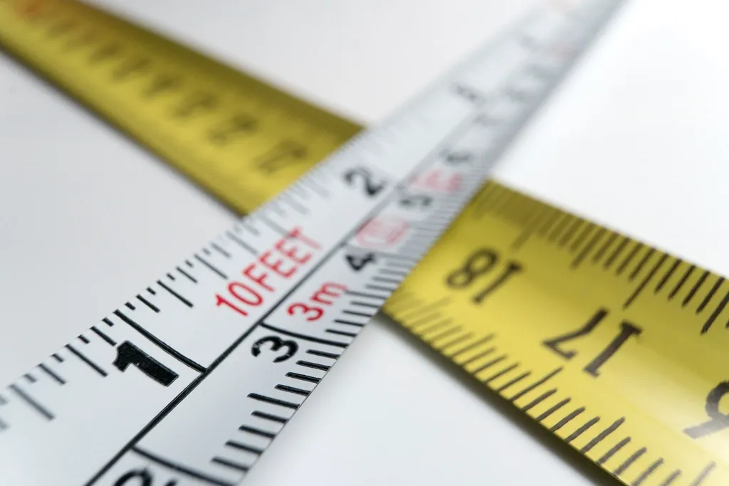 Two measuring tapes crossed on a white surface