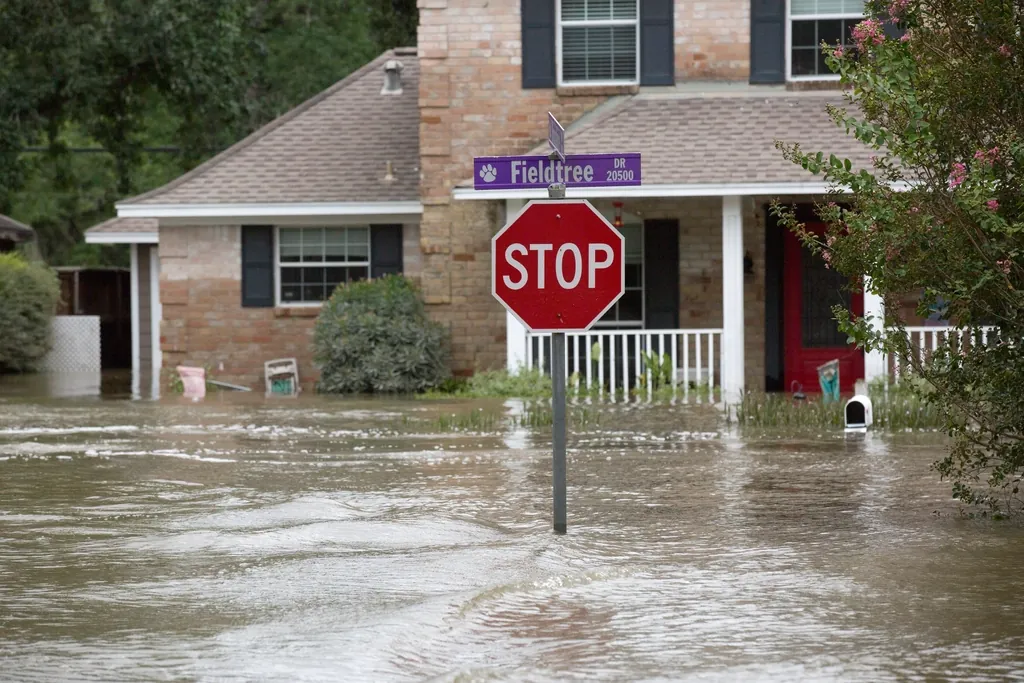 Floodwater covering a residential street in front of a brick house