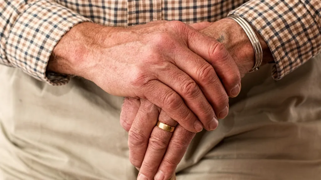 Older adult's hands resting on a wooden cane, a reminder of what in-home senior care in NJ supports