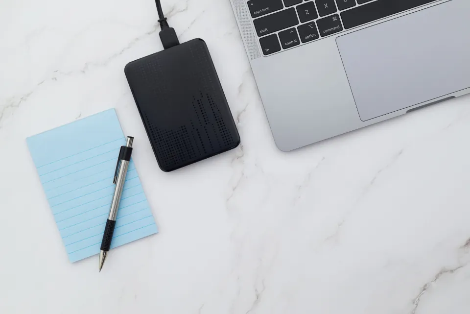 External backup drive connected to a laptop on a white desk