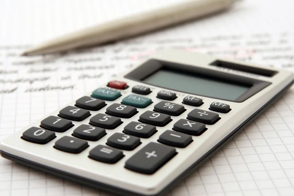Desk calculator and a pen resting on handwritten notes