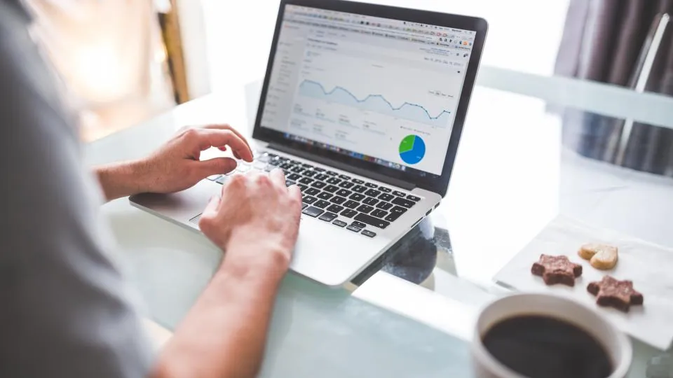 Hands on a laptop showing charts, checking reports from an outsourced payroll in NJ service