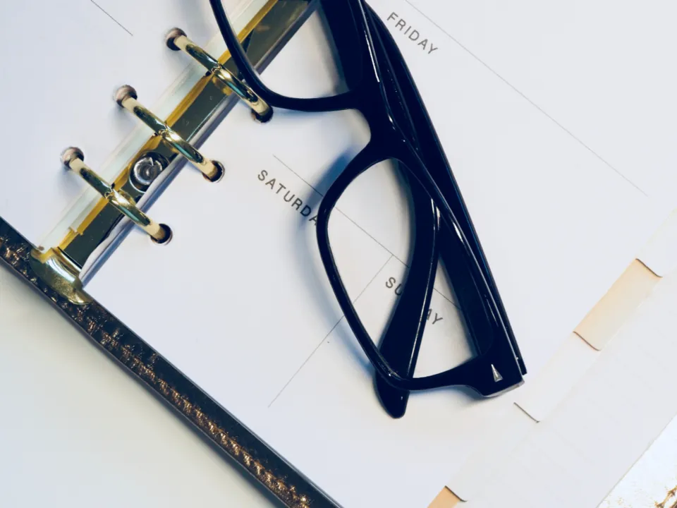 Open weekly planner with eyeglasses resting on the pages