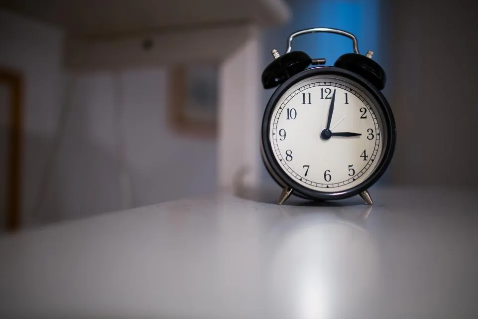 Black alarm clock on a white table in a quiet room