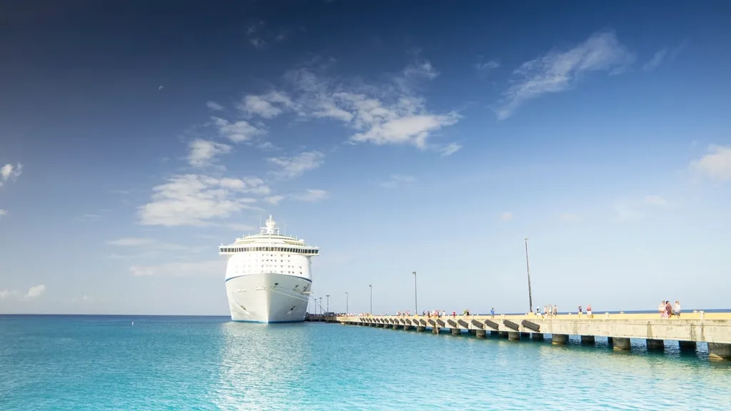 Cruise ship docked at a long pier in clear turquoise water, a goal when you plan a family cruise