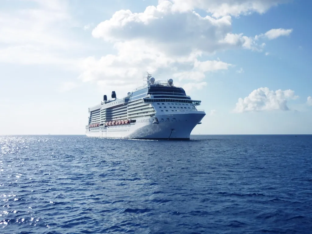 Large white cruise ship sailing on open blue sea under a sunny sky