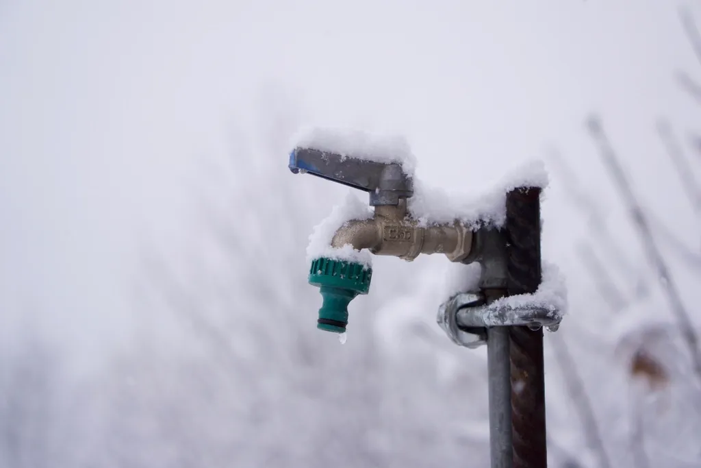 Outdoor water spigot covered in snow and frost Outdoor water spigot covered in snow and frost