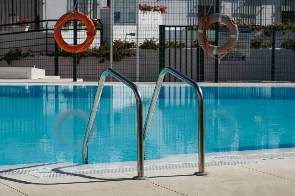Pool steps with steel handrails and life rings on a fence
