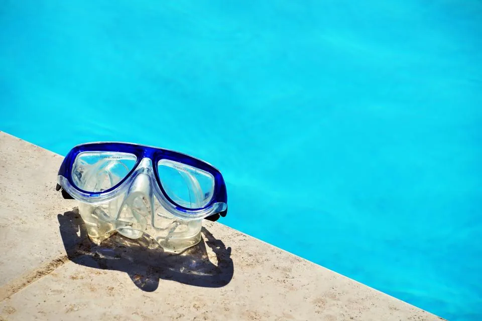 Swim goggles resting on the edge of a pool