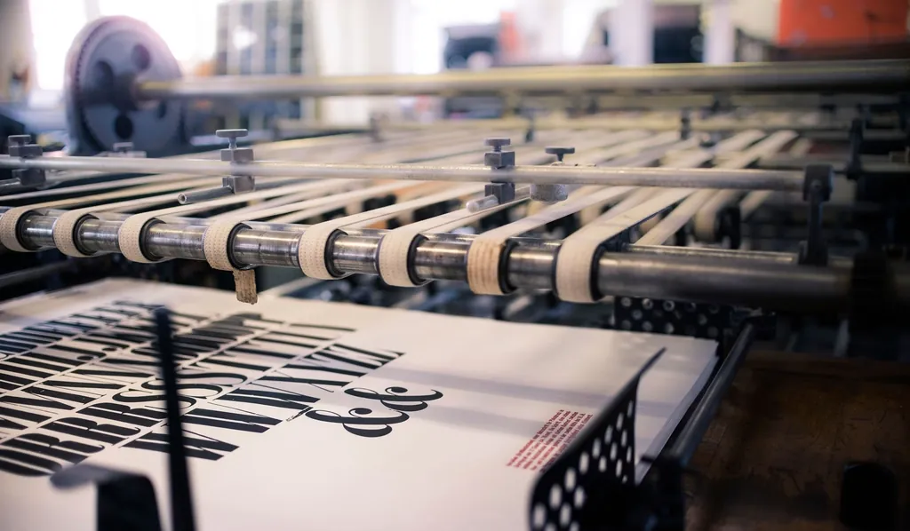 Printed sheets moving through the rollers of a printing press