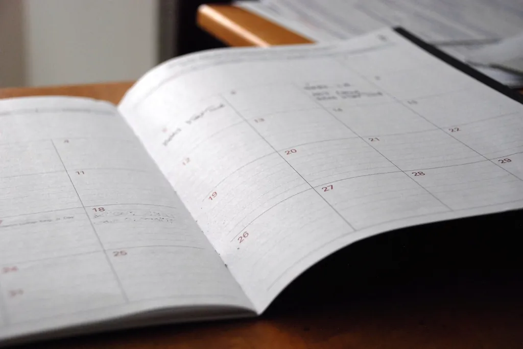 Open paper calendar with short notes written on the dates